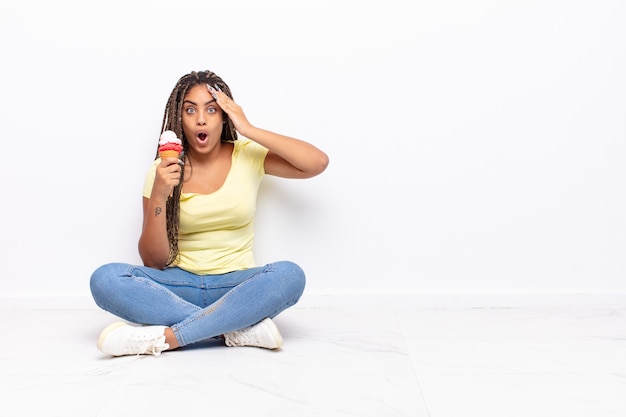 Joven mujer afro mirando feliz, asombrado y sorprendido