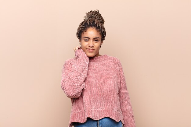 Joven mujer afro que se siente estresada, frustrada y cansada, frotando el cuello doloroso, con una mirada preocupada y preocupada