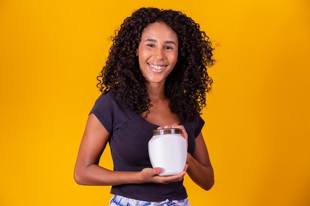 Joven mujer afro sosteniendo en las manos un paquete de crema para el cabello