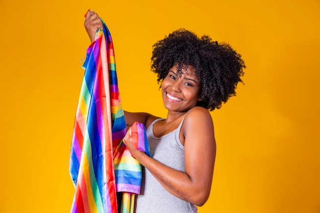 Joven mujer afro sosteniendo en sus manos una bandera lgbt orgullo gay