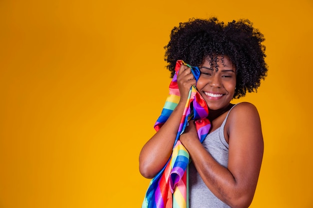 Joven mujer afro sosteniendo en sus manos una bandera lgbt orgullo gay