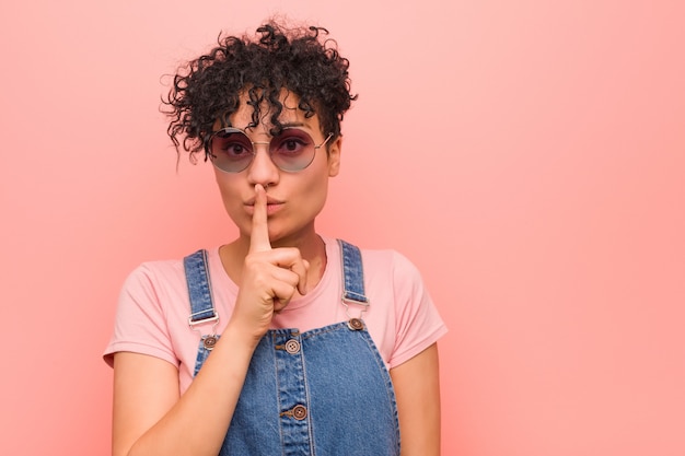 Joven mujer afroamericana adolescente mixta guardar un secreto o pedir silencio.