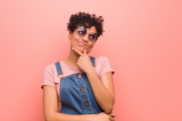 Joven mujer afroamericana adolescente mixta mirando hacia los lados con expresión dudosa y escéptica.