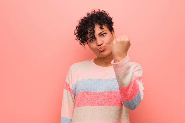 Joven mujer afroamericana adolescente mixta mostrando el puño a la cámara, agresiva expresión facial.