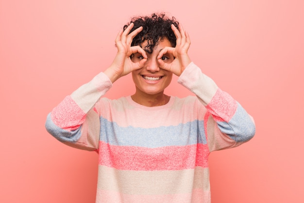 Joven mujer afroamericana adolescente mixta mostrando signo bien sobre los ojos