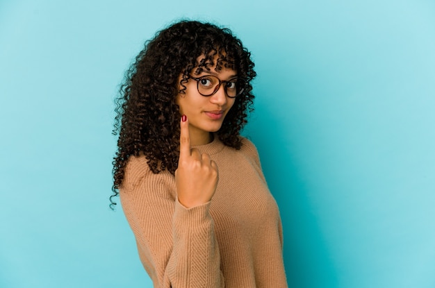 Joven mujer afroamericana afro aislada señalando con el dedo como si invitara a acercarse.