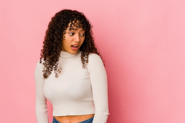 Foto joven mujer afroamericana afro aislada está sorprendida por algo que ha visto.