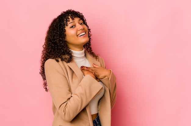 Joven mujer afroamericana afro aislada tiene expresión amistosa, presionando la palma contra el pecho. Concepto de amor.