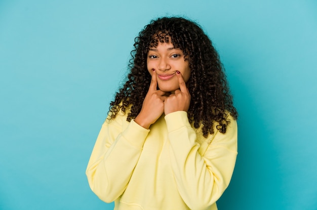 Joven mujer afroamericana afro dudando entre dos opciones.