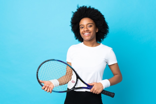 Joven mujer afroamericana aislada en azul jugando tenis