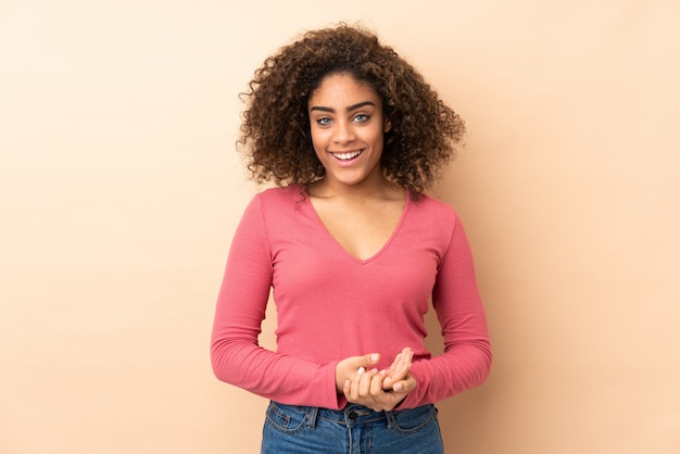 Joven mujer afroamericana aislada en beige riendo