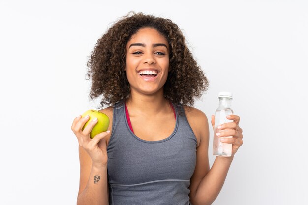 Joven mujer afroamericana aislada en blanco con una manzana y con una botella de agua