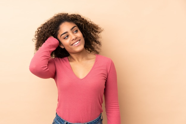 Joven mujer afroamericana aislada en espacio beige pensando en una idea