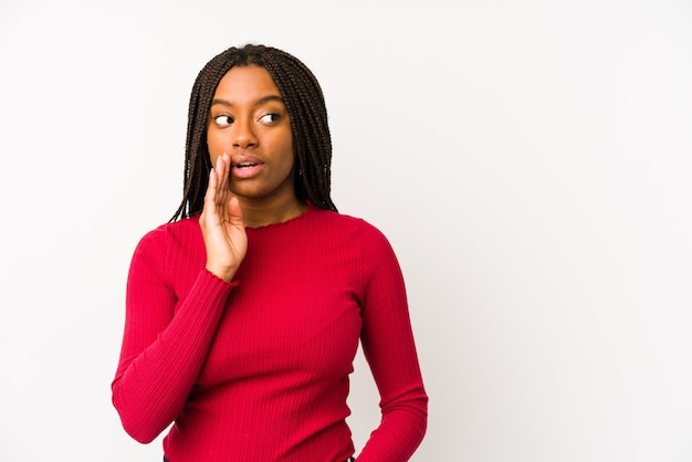 Joven mujer afroamericana aislada está diciendo una noticia secreta de frenado en caliente y mirando a un lado