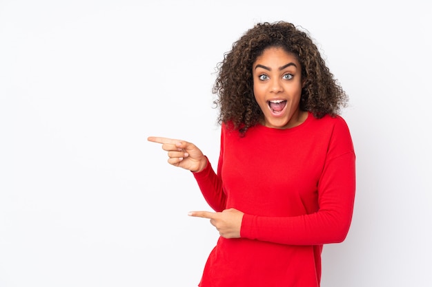 Joven mujer afroamericana aislada en el lado sorprendido y apuntando