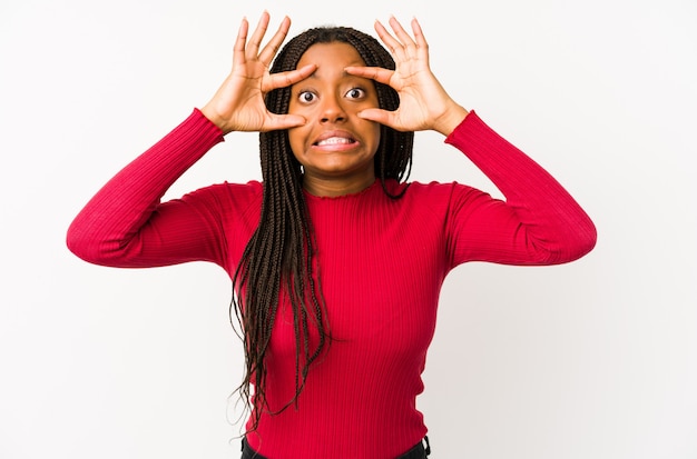 Joven mujer afroamericana aislada manteniendo los ojos abiertos para encontrar una oportunidad de éxito.