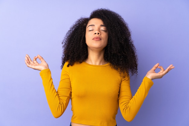 Joven mujer afroamericana aislada en púrpura en pose zen