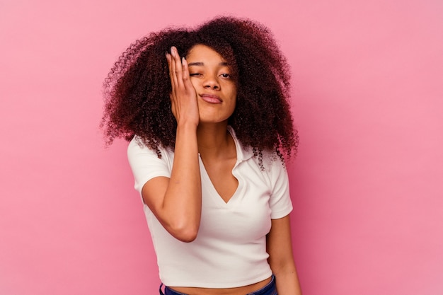 Joven mujer afroamericana aislada en rosa cansada y muy somnolienta manteniendo la mano en la cabeza.