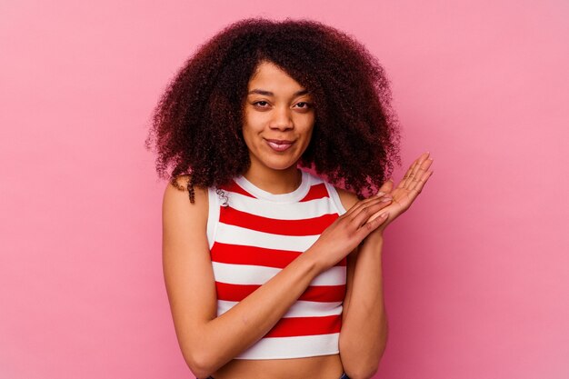 Joven mujer afroamericana aislada en rosa sintiéndose enérgica y cómoda, frotándose las manos con confianza.