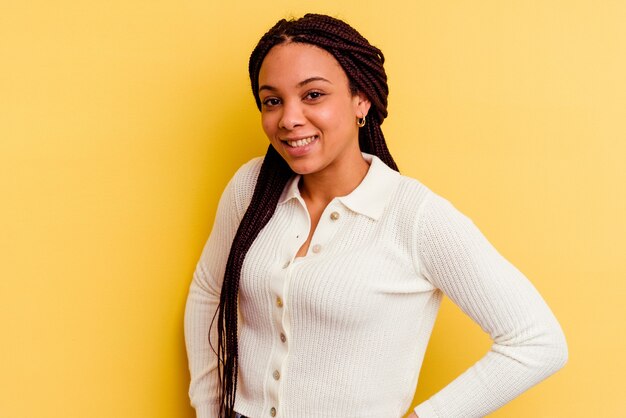 Joven mujer afroamericana aislada sobre fondo amarillo feliz, sonriente y alegre.