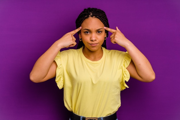 Joven mujer afroamericana aislada sobre fondo amarillo Joven mujer afroamericana aislada sobre fondo amarillo se centró en una tarea, manteniendo los dedos índice apuntando a la cabeza.