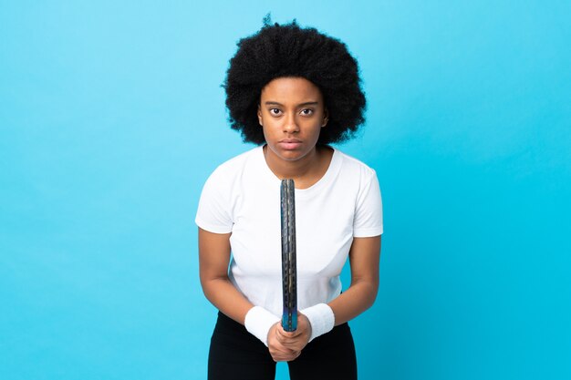 Joven mujer afroamericana aislada sobre fondo azul jugando tenis