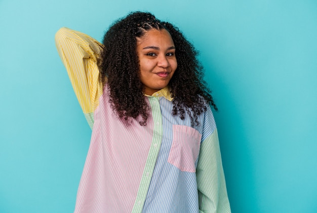 Joven mujer afroamericana aislada sobre fondo azul que sufre dolor de cuello debido al estilo de vida sedentario.