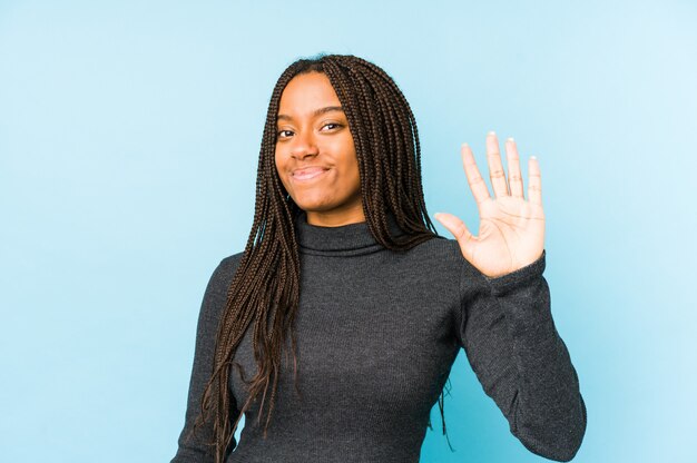 Joven mujer afroamericana aislada sobre fondo azul sonriente alegre mostrando número cinco con los dedos.