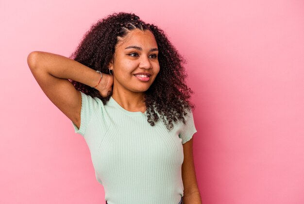 Joven mujer afroamericana aislada sobre fondo rosa cansada y con mucho sueño manteniendo la mano en la cabeza.