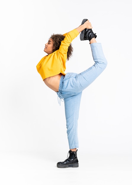 Joven mujer afroamericana bailando sobre pared blanca