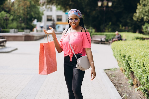 Joven mujer afroamericana en la calle con bolsas de compras