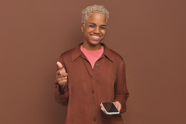 Joven mujer afroamericana carismática feliz señala con el dedo los soportes de la pantalla