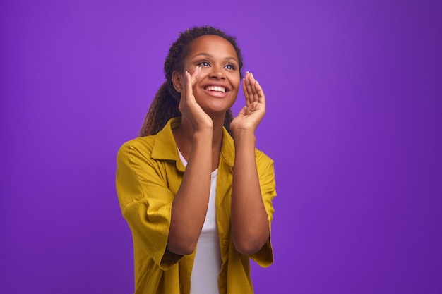 Joven mujer afroamericana casual positiva grita y se lleva las manos a la boca