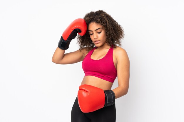 Joven mujer afroamericana deporte en pared blanca con guantes de boxeo