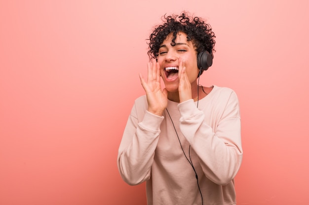 Joven mujer afroamericana escuchando música gritando emocionado al frente