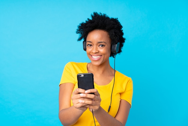 Joven mujer afroamericana escuchando música con un móvil