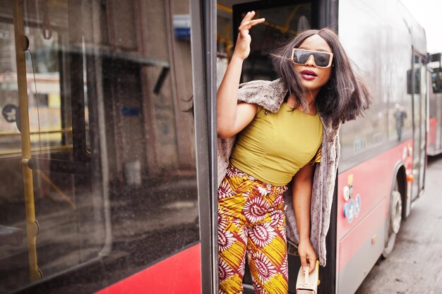 Joven mujer afroamericana con estilo en gafas de sol modernas en un autobús