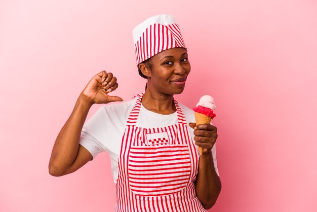 Joven mujer afroamericana fabricante de helados sosteniendo helado aislado sobre fondo rosa se siente orgullosa y segura de sí misma, ejemplo a seguir.