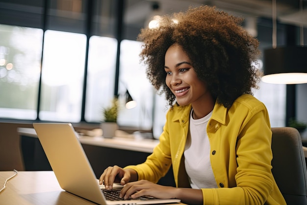 Joven mujer afroamericana feliz con chaqueta amarilla trabajando en una computadora portátil