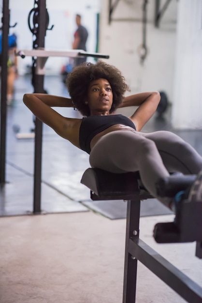 Joven mujer afroamericana en forma haciendo abdominales en el gimnasio en el gimnasio. Ejercicios abdominales Siéntese