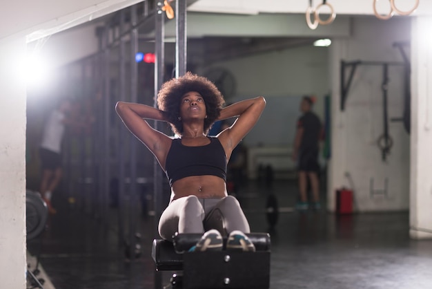 Joven mujer afroamericana en forma haciendo abdominales en el gimnasio en el gimnasio. Ejercicios abdominales Siéntese