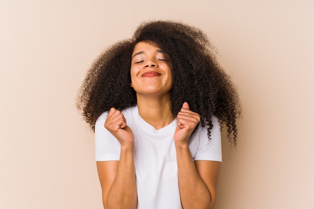 Joven mujer afroamericana levantando el puño, sintiéndose feliz y exitoso. Concepto de victoria