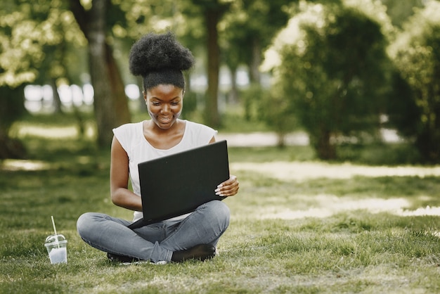 Una joven mujer afroamericana mirando en un portátil en el parque