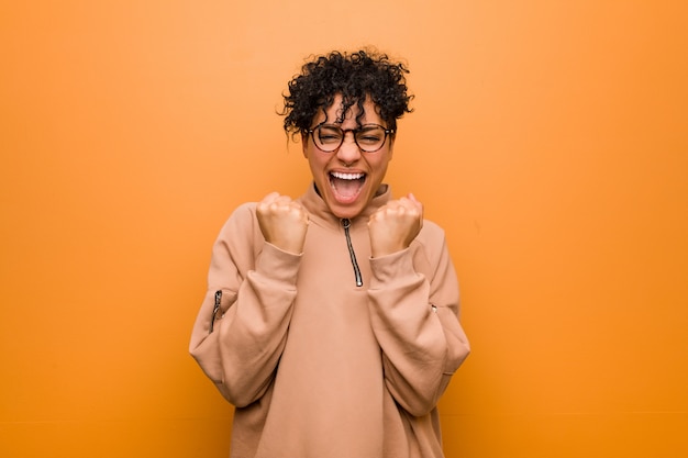 Joven mujer afroamericana mixta contra un fondo marrón