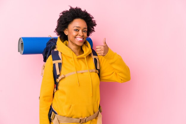 Joven mujer afroamericana mochilero aislada sonriendo y levantando el pulgar hacia arriba