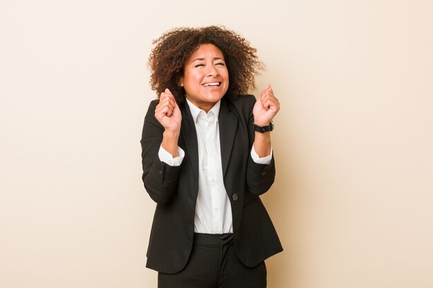 Joven mujer afroamericana de negocios levantando el puño, sintiéndose feliz y exitoso. Concepto de victoria