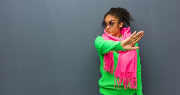 Joven mujer afroamericana con ojos azules, poniendo la mano delante