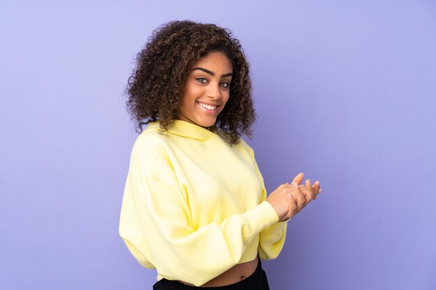 Joven mujer afroamericana en pared aplaudiendo