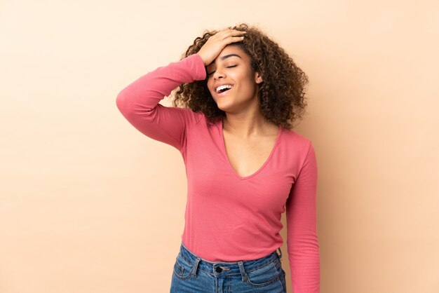 Joven mujer afroamericana en pared beige se ha dado cuenta de algo y tiene la intención de la solución