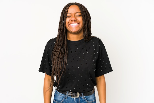 Joven mujer afroamericana en la pared blanca se ríe y cierra los ojos, se siente relajado y feliz.